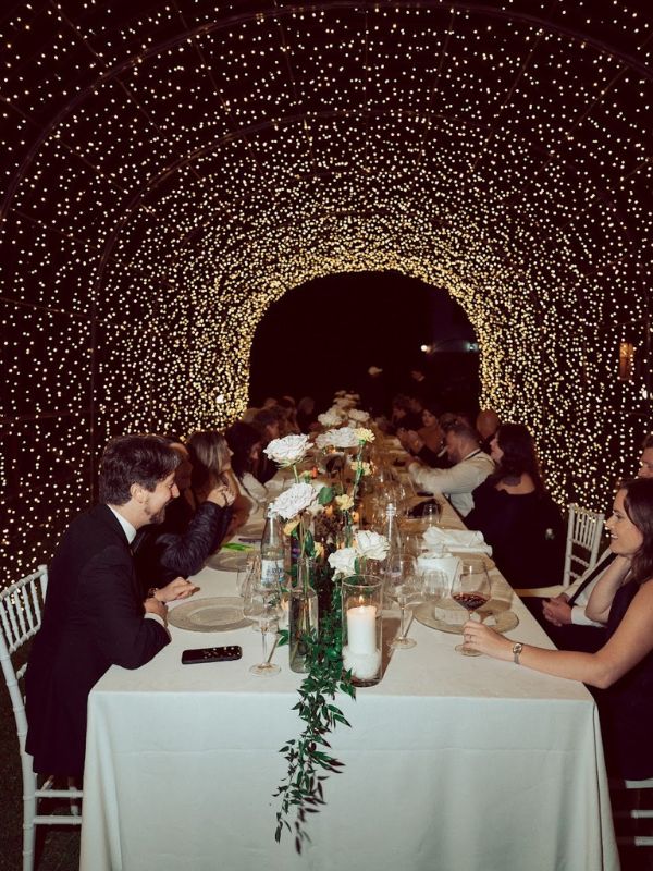Matrimonio esclusivo in Toscana: coppia al banchetto nuziale con centro tavola floreale e sfondo luminoso stellato
