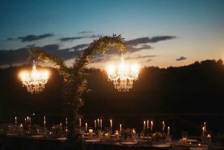 Tavoli eleganti con candele e lampadari luminosi per un evento serale all'aperto, organizzato da un'Agenzia Wedding Planner