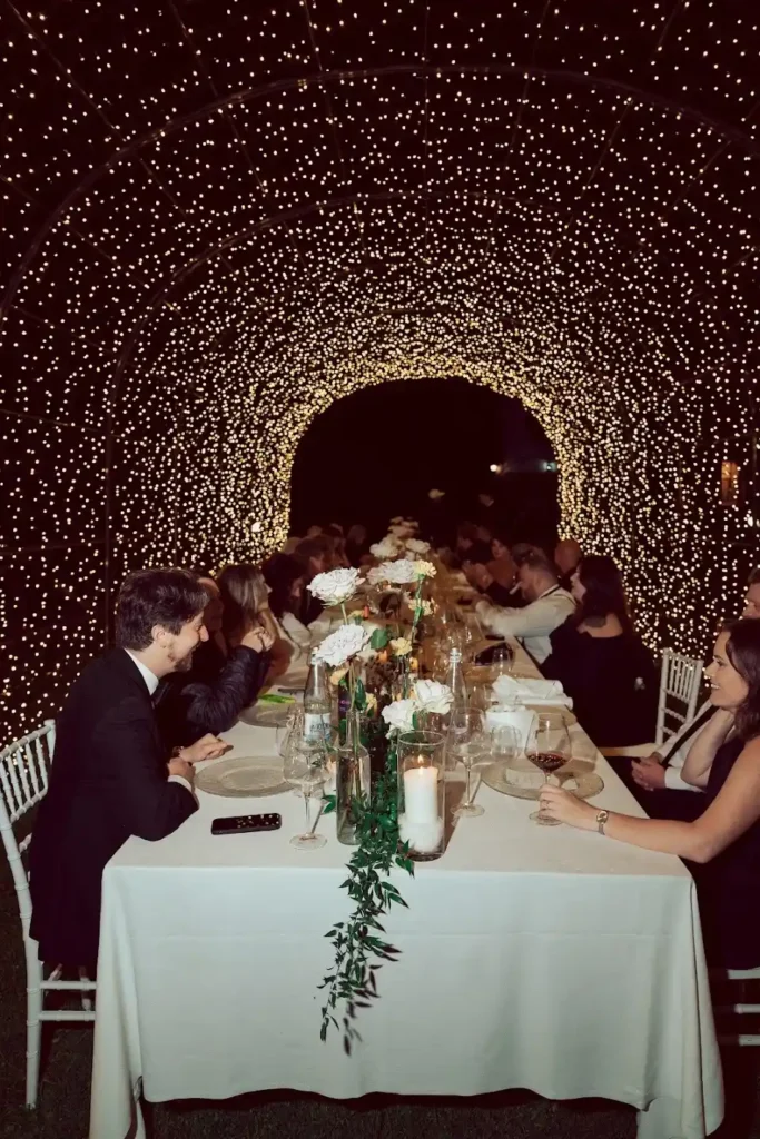 Tavolo elegante wedding con decorazioni floreali e luci stellari, evento serale con ospiti in abito formale