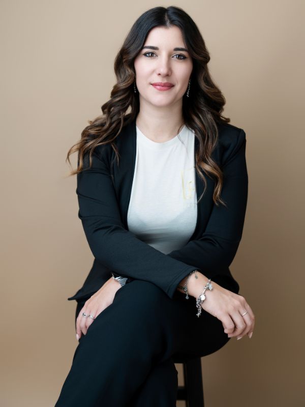 Donna professionale con giacca elegante in posa seduta, abbigliamento formale per occasioni speciali e Destination Wedding