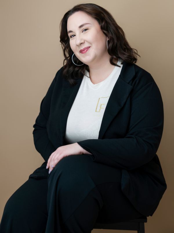 Donna professionale sorridente con giacca elegante e maglioncino bianco, ideale per location per matrimoni raffinati